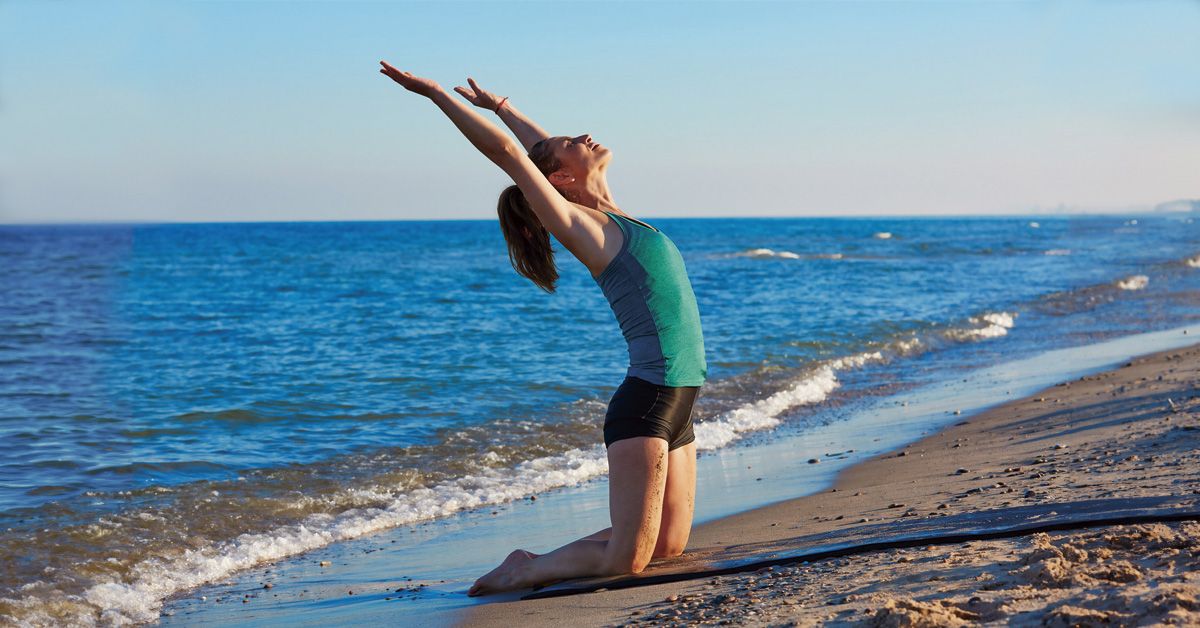 Mujer practicando yoga en la orilla de la playa